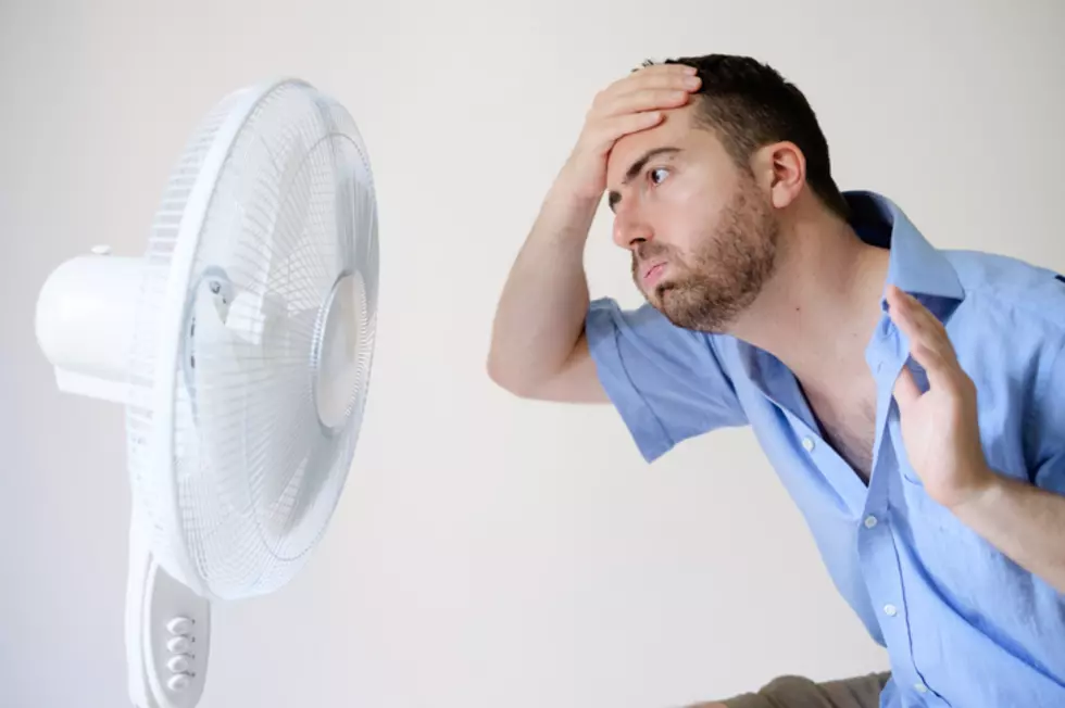 Flushed man feeling hot in front of a fan