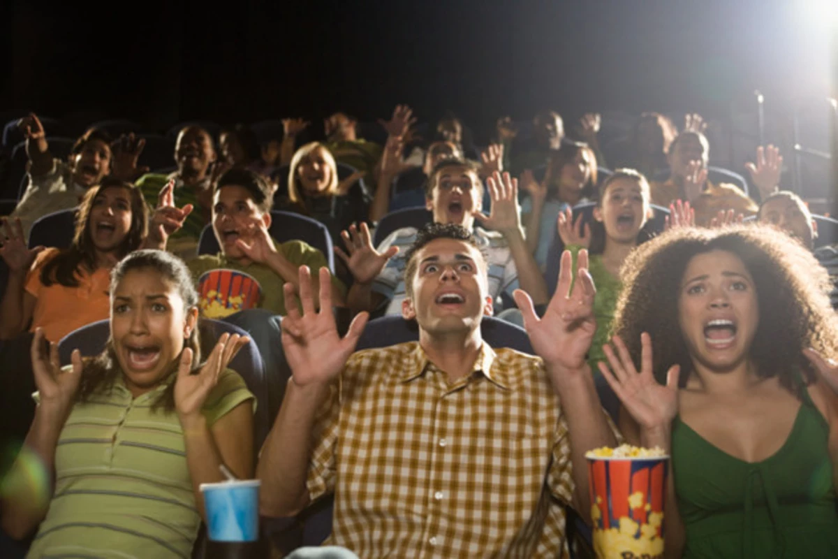 A diverse group of people in a movie theater with various reactions to the movie they're watching.