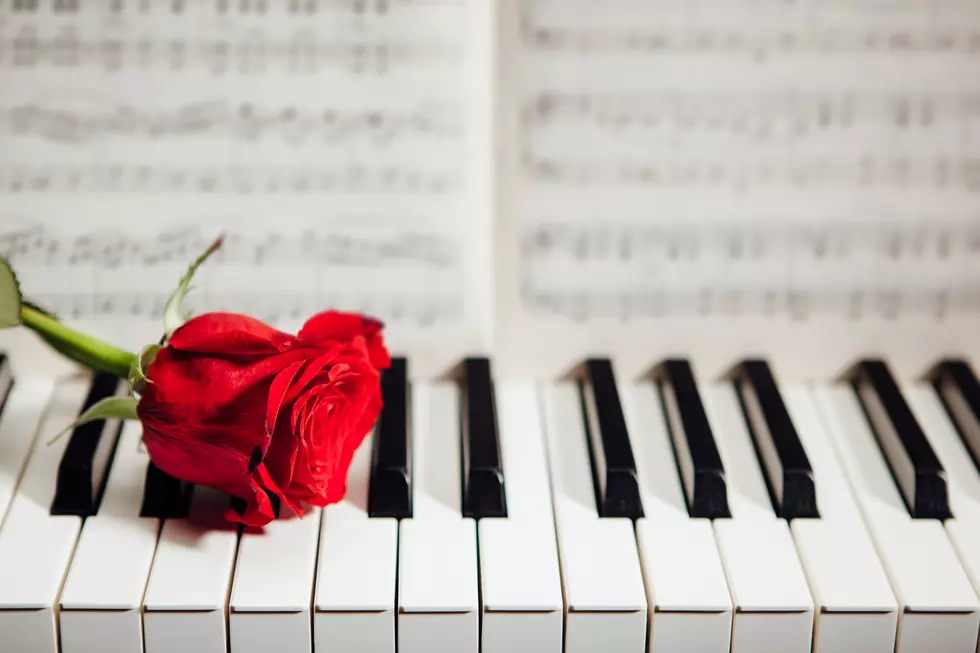 red rose on piano keys and music book