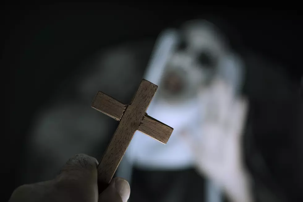 closeup a cross in the hand of a man and a frightening evil nun, wearing a typical black and white habit, screaming