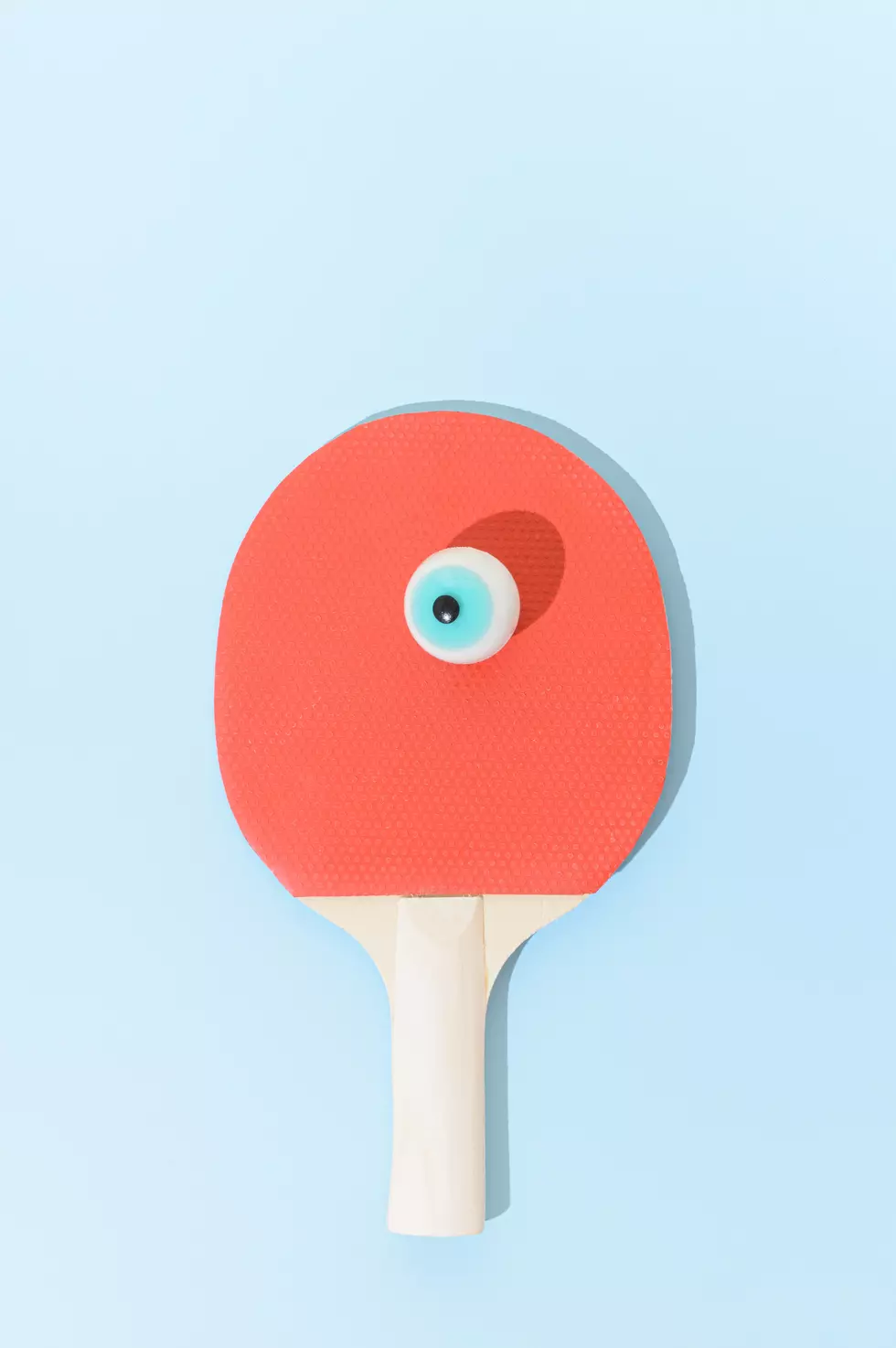 A table tennis racket with a false eye instead of a ball. Surreal sport ping pong competitive concept.