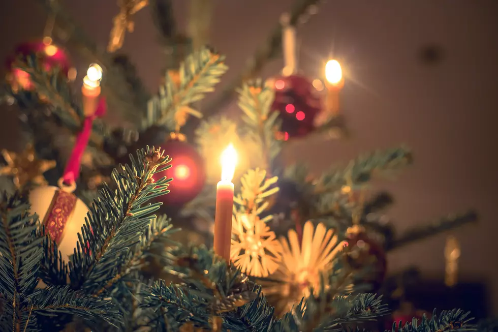 Candle on traditional decorated Christmas tree, evening