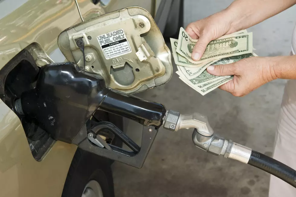 Horizontal shot of someone's hands holding money at the gas pump
