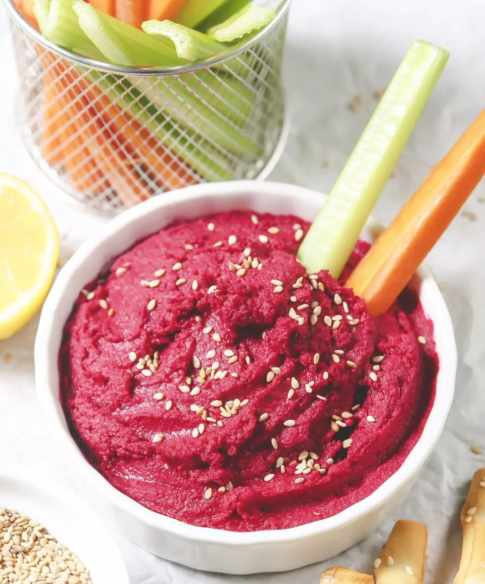 Bowl of beetroot hummus, sesame, carrot and celery crudites and breadsticks