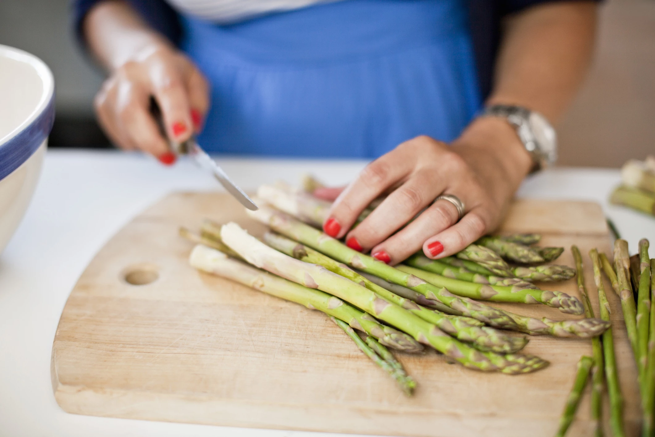 Close-up of woman chopping asparagus on cutting board