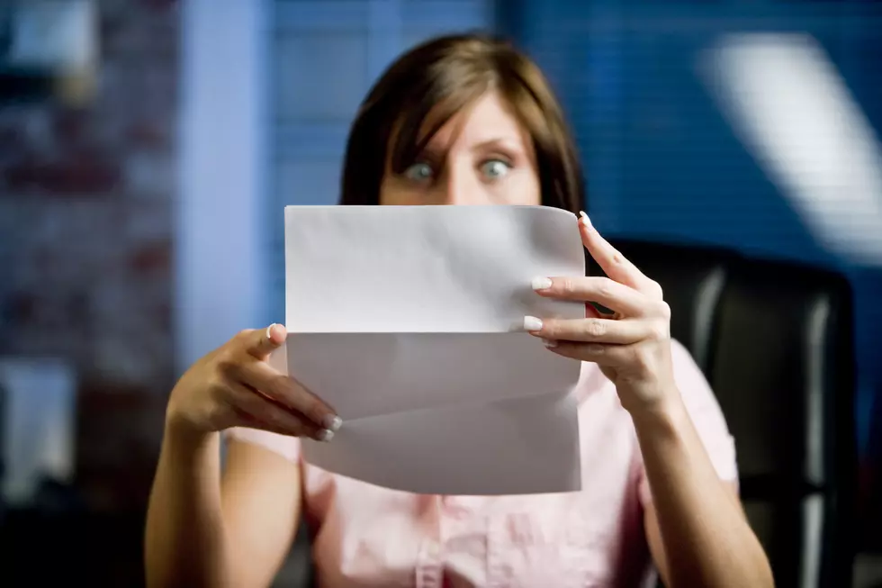 A woman looking at her mail (letter or bills) in disbelief, shock!