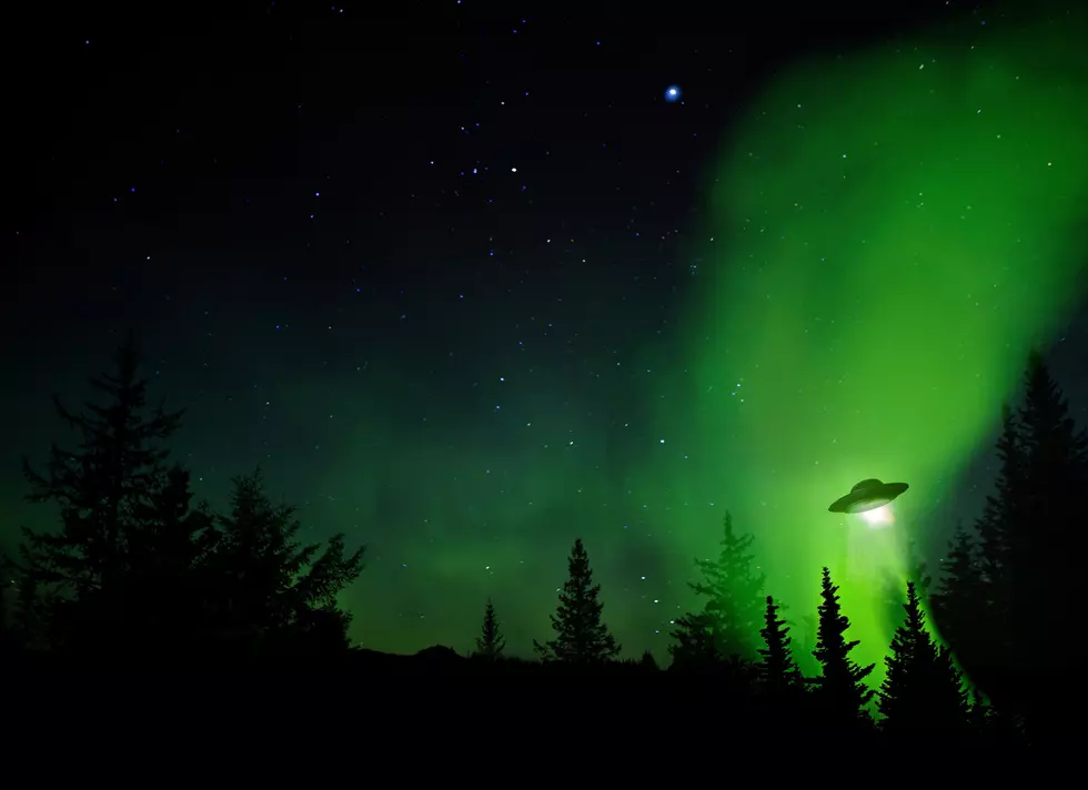 UFO landing at night in the forest with trees and stars.